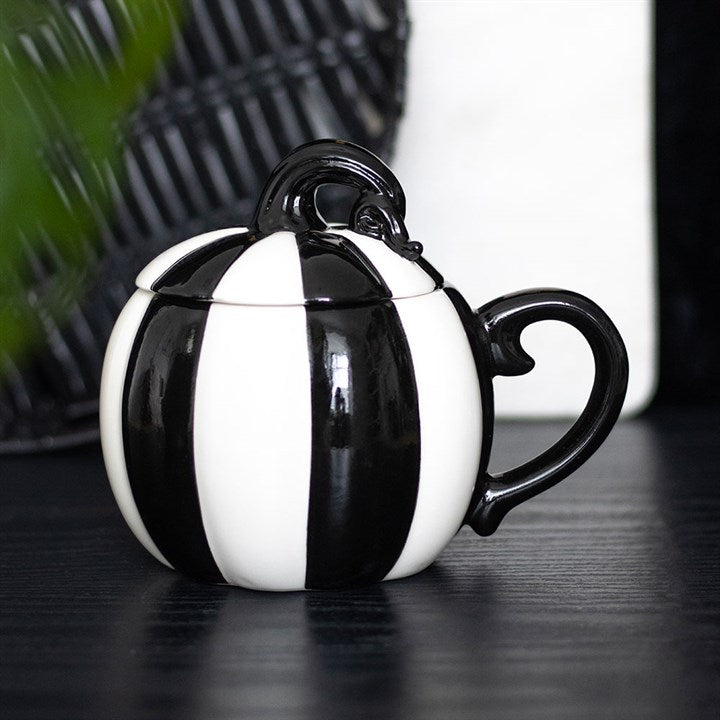 Black and white striped teapot on a dark surface with a blurred background