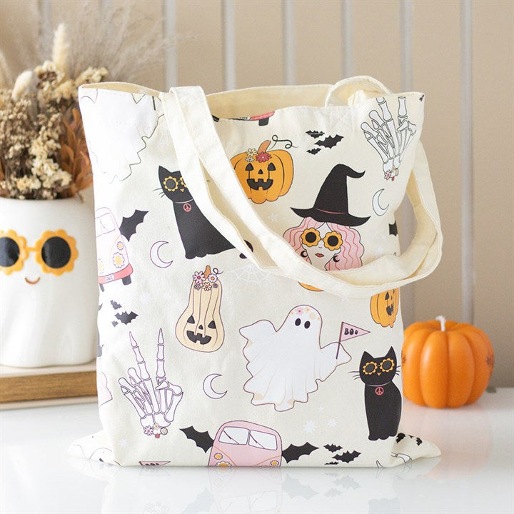 Tote bag with Halloween-themed design featuring cats, ghosts, and pumpkins on a neutral background.