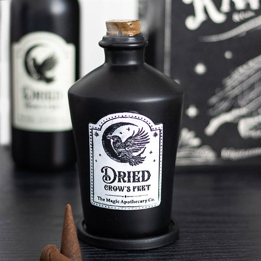 Black bottle labeled 'Dried Crow's Fert' with a white label featuring an eagle design, on a dark surface.