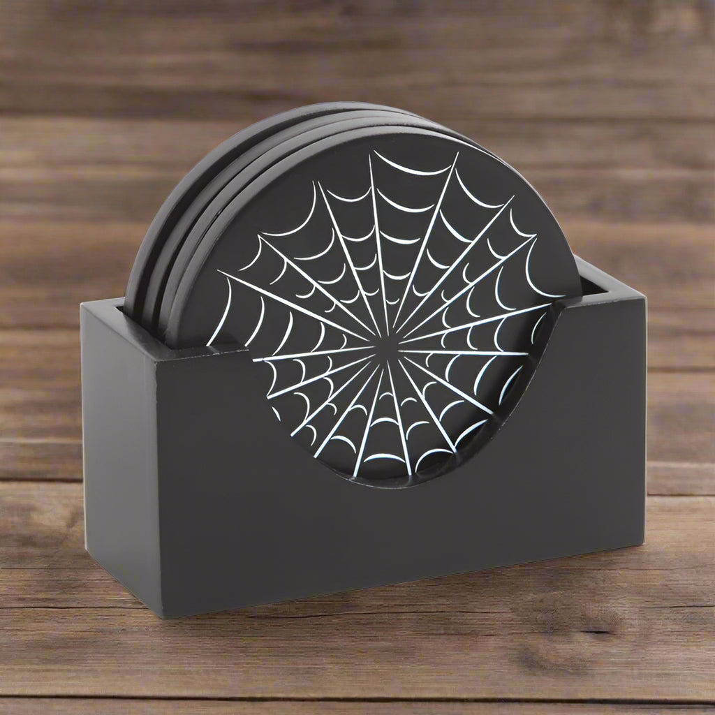 Set of black coasters with spider web design in a holder on a wooden table