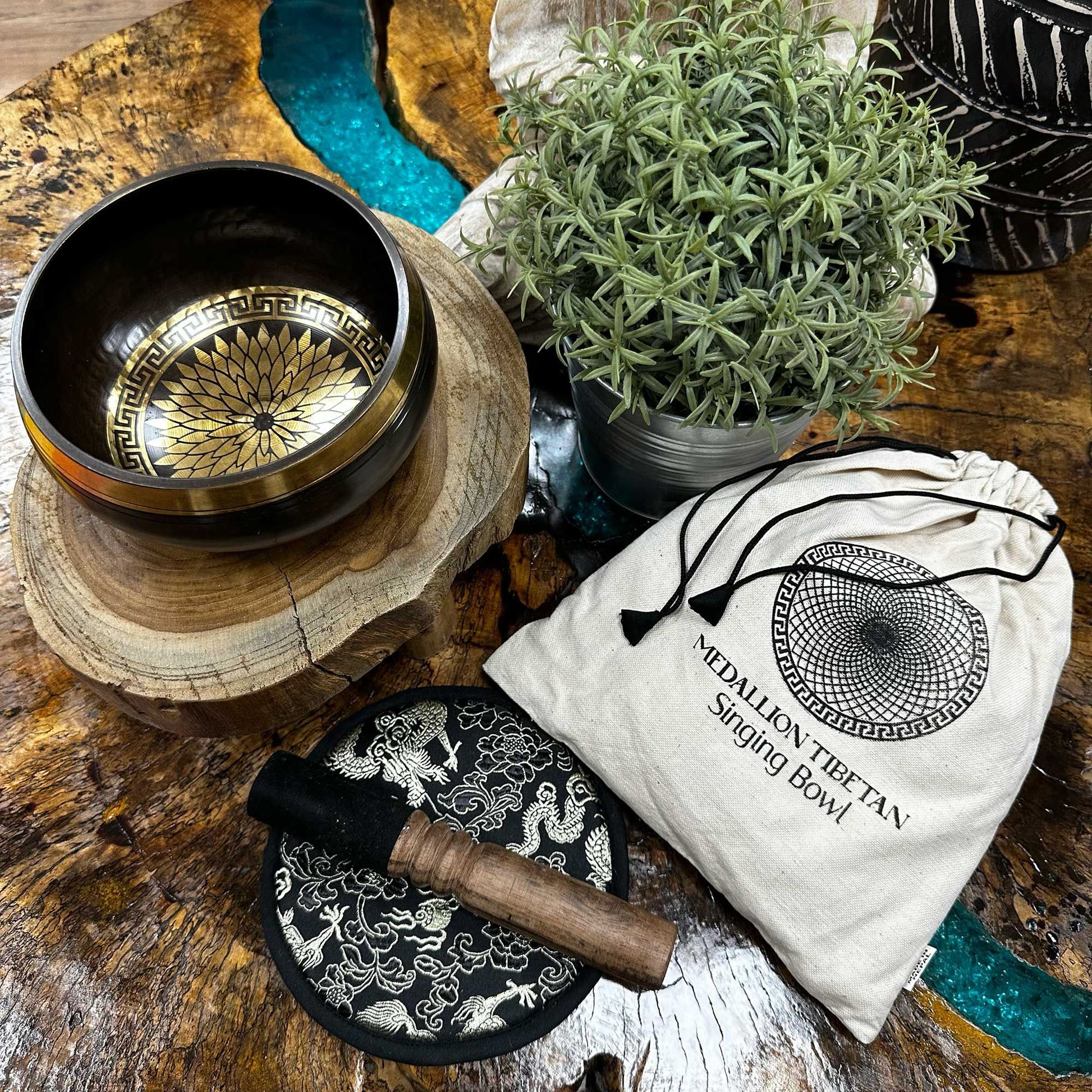 Tibetan singing bowl set with decorative bag on a wooden surface