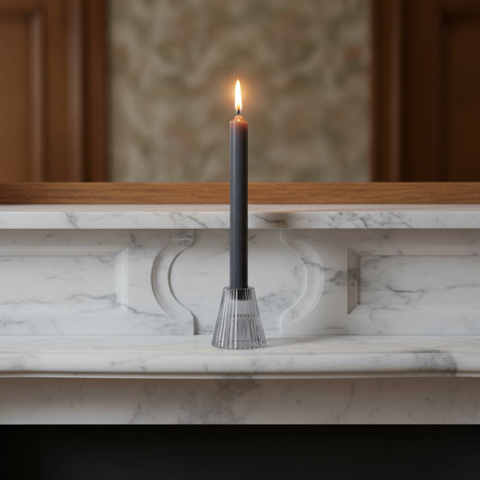 Black candle in a decorative holder on a marble ledge with a blurred background