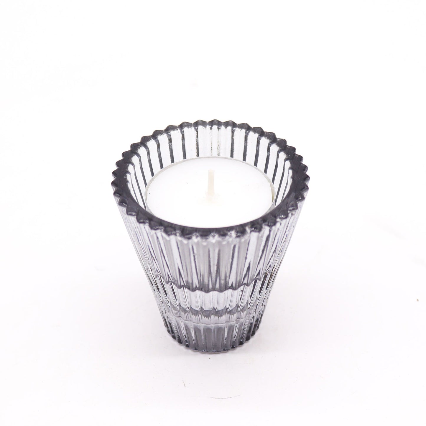 Clear glass candle holder with a white candle on a white background