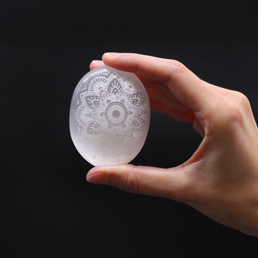 Hand holding a crystal egg with intricate patterns against a black background