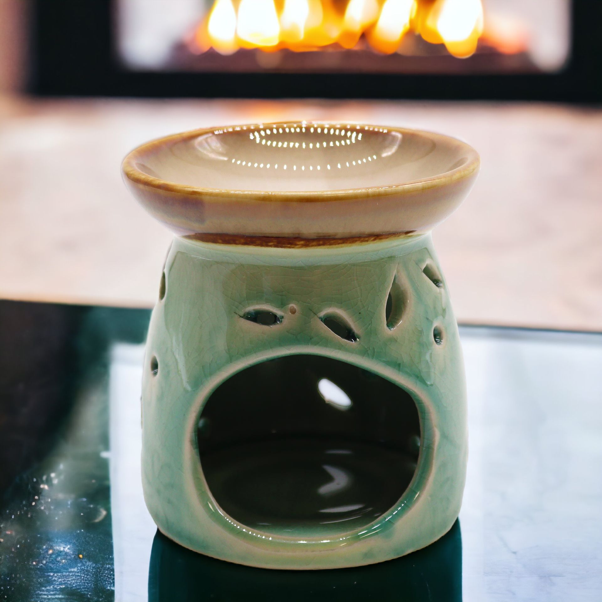 Classic blue ceramic oil burner glowing on a table with a fire in the background.