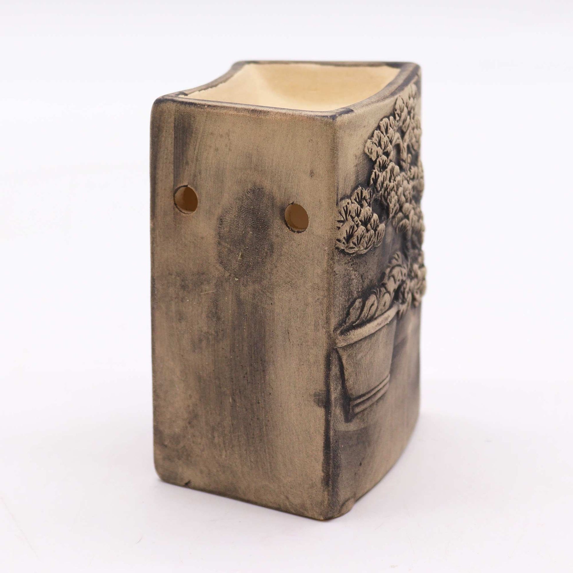Side angle of bonsai oil burner with ventilation holes and sculpted texture.