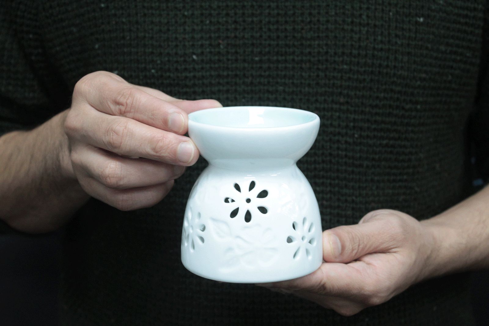 Close-up of a glossy white ceramic oil burner with petal-shaped cut-outs