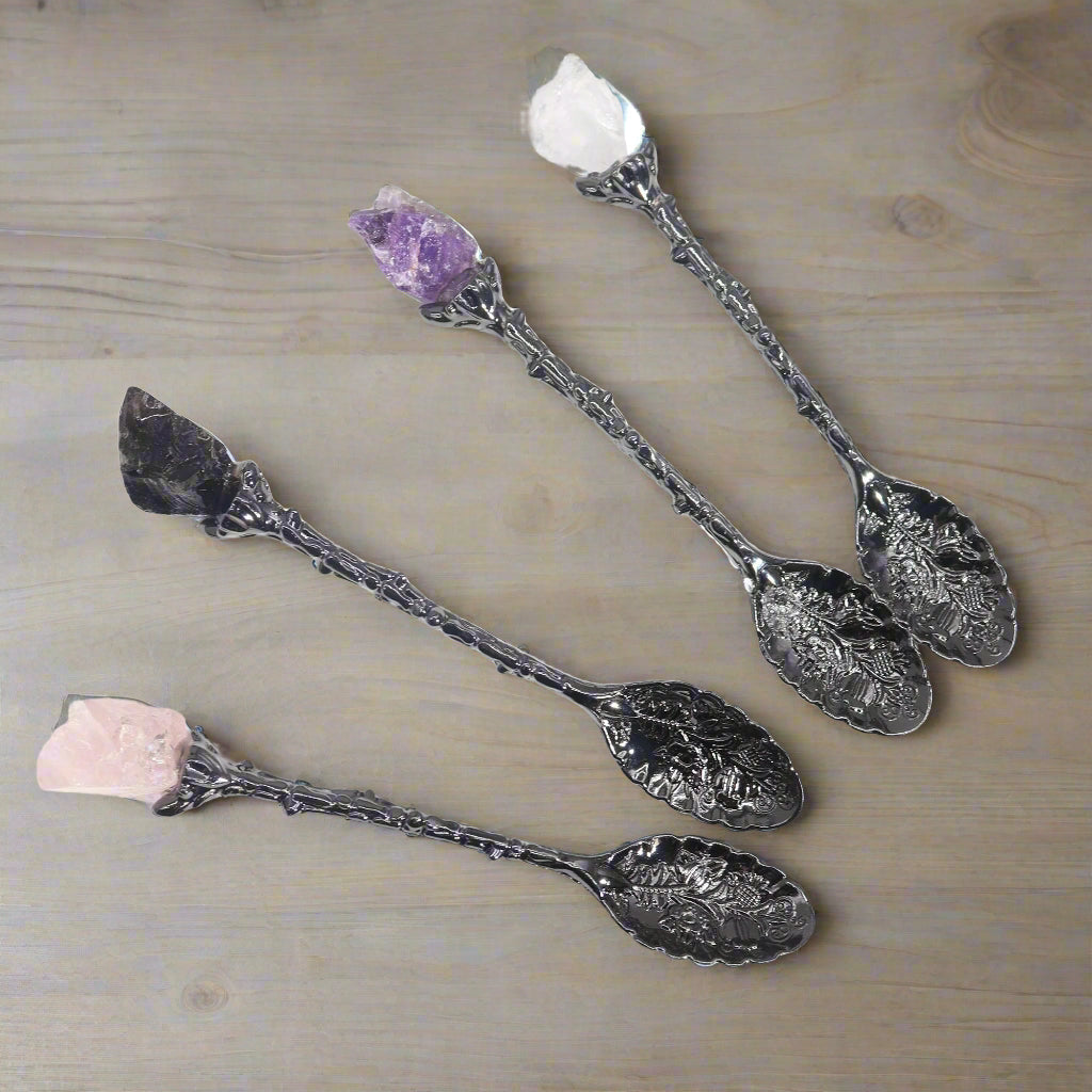 Four spoons laid out on a white surface highlighting floral-etched bowls and crystal tips.