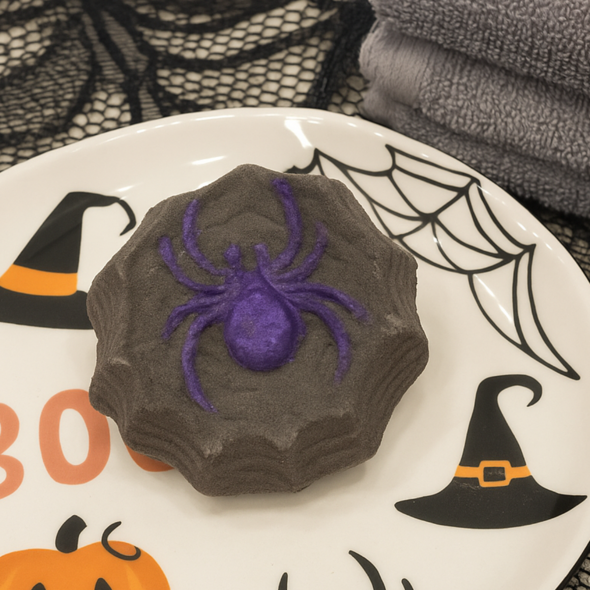 Halloween-themed bath bomb with a purple spider on a decorative plate