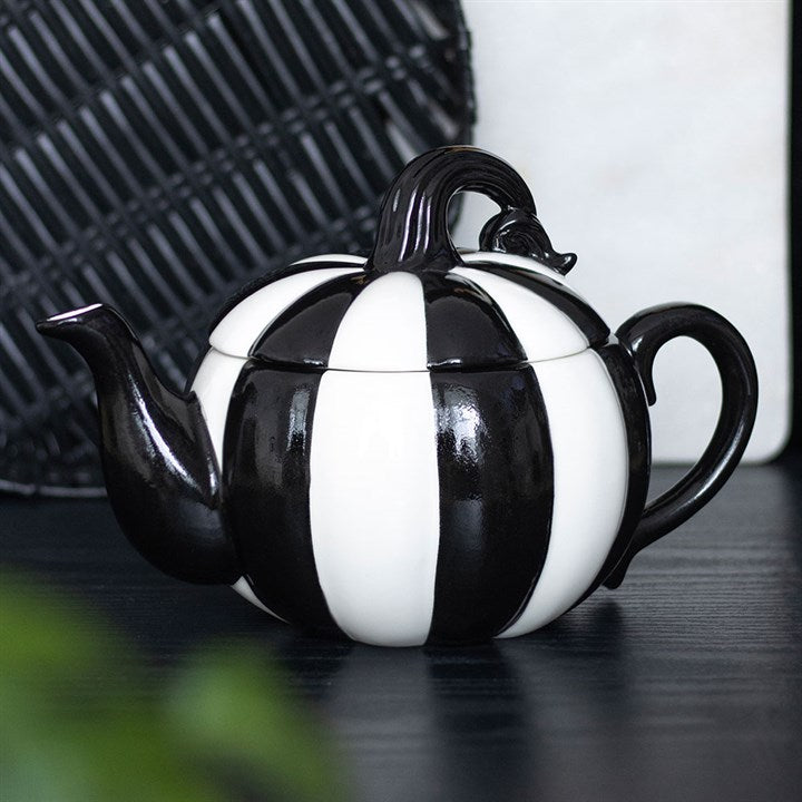 Black and white striped teapot on a dark surface with blurred background