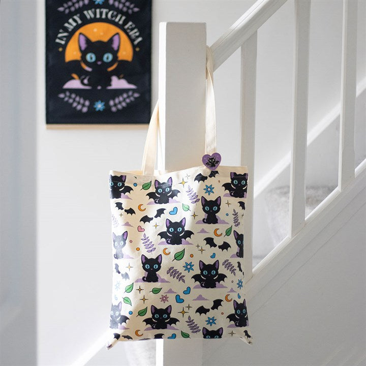 Tote bag with black cat and bat pattern hanging on a white staircase.