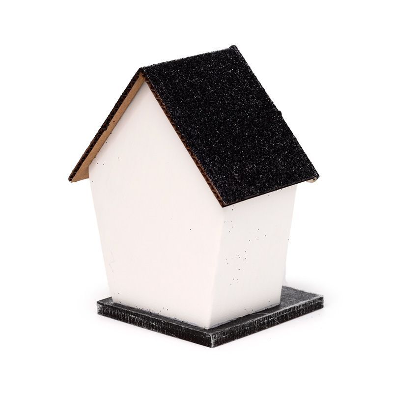Small white haunted house with glittery black roof, spider web windows and warm LED glow.