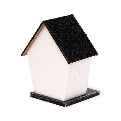 Small white haunted house with glittery black roof, spider web windows and warm LED glow.