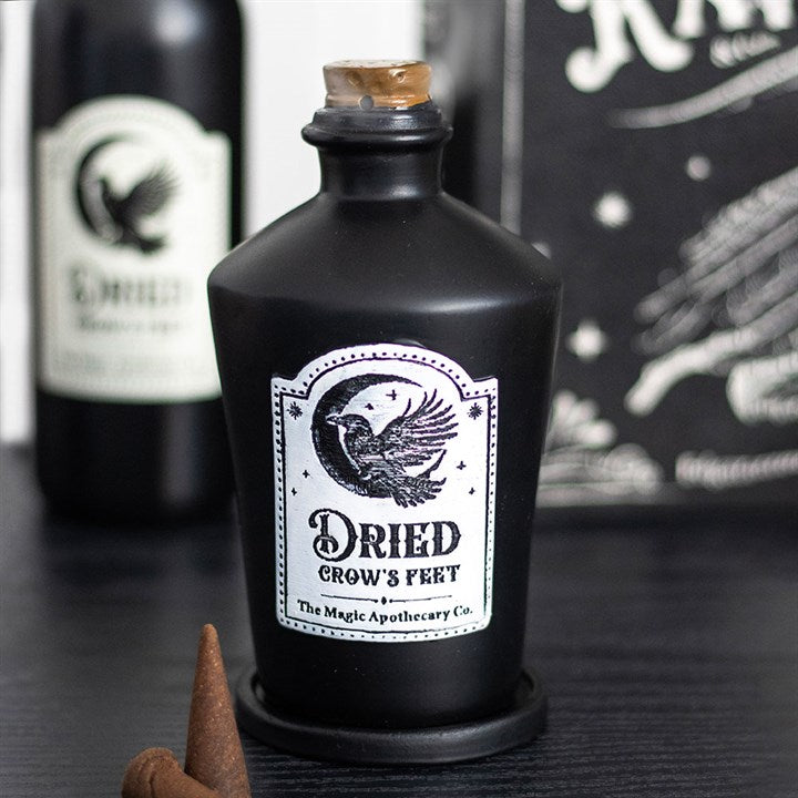 Black bottle labeled 'Dried Crow's Fert' with a white label featuring an eagle design, on a dark surface.