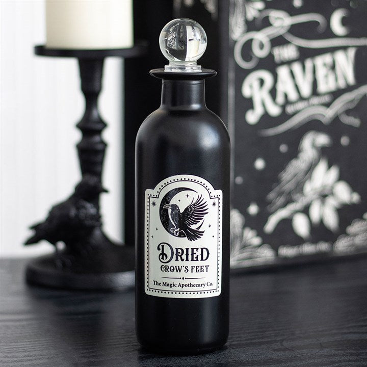 Black bottle labeled 'Dried Crow's Feet' with decorative elements on a dark surface.