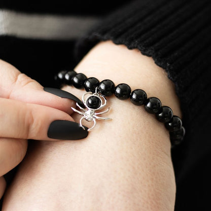 Black beaded bracelet with a spider charm worn on a wrist.