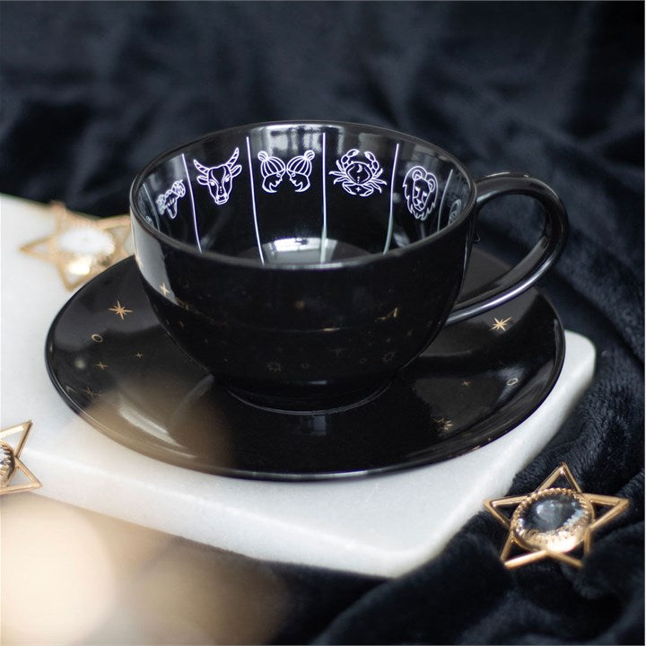 Black ceramic cup and saucer with star and moon designs on a dark background