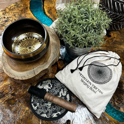Tibetan singing bowl set with decorative bag on a wooden surface