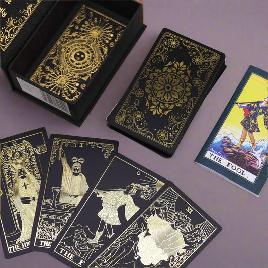 Black tarot cards with gold designs and a few cards displayed on a lilac background.