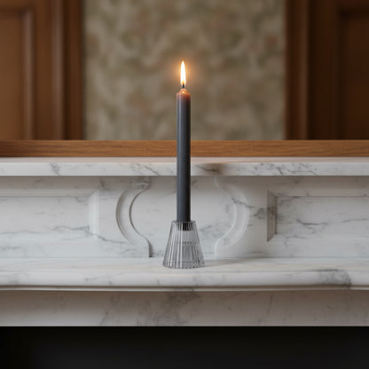 Black candle in a decorative holder on a marble ledge with a blurred background