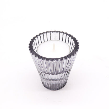 Clear glass candle holder with a white candle on a white background