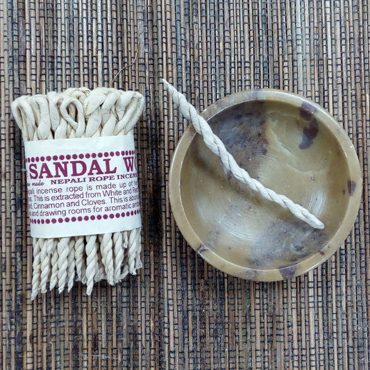 Sandalwood incense sticks with packaging and a sandalwood bowl on a textured surface