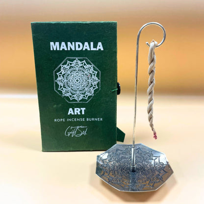 Metallic incense burner with rope and green box labeled 'Mandala Art' on a beige background