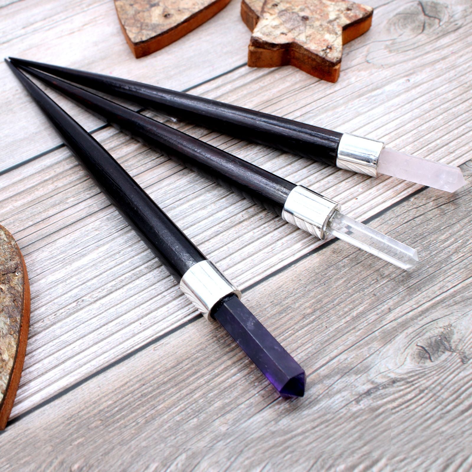 Three black and silver wands on a wooden surface