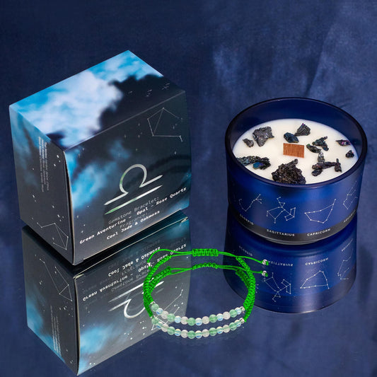 Blue candle with decorative stones, packaging, and a green bracelet on a dark blue background