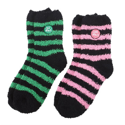 Two pairs of fluffy striped socks in black/pink and black/green with “Good Witch” and “Bad Witch” badges