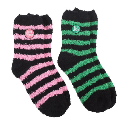 Two pairs of fluffy striped socks in black/pink and black/green with “Good Witch” and “Bad Witch” badges