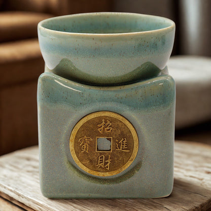 Lifestyle shot of the jade burner on a wooden surface; the prosperity coin emblem is centred and the bowl is seated on top.