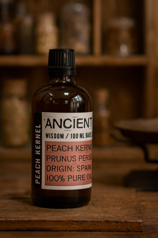 Amber glass bottle with black cap labelled ‘Peach Kernel—cold-pressed’; a light golden Prunus persica kernel oil from Spain with a delicate aroma and fast-absorbing, silky feel.